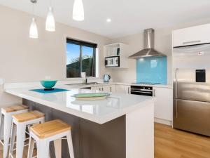 a kitchen with a large white island with stools at Pisa Oasis - Cromwell Holiday Home in Cromwell