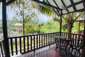 Zimmer mit einem Tisch und Stühlen auf einem Balkon in der Unterkunft Hotel dan Gazebo Pinggir Kali Prigen Mitra RedDoorz in Pasuruan