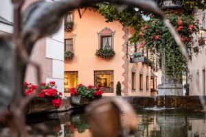 un edificio con flores frente a un canal en Hotel Cavallino D'Oro Bed&Breakfast, en Castelrotto