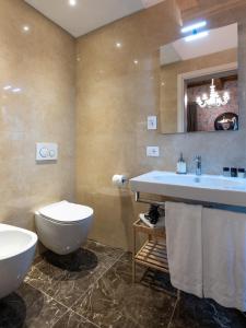 uma casa de banho com 2 lavatórios, um WC e um espelho. em Kairos by Florence Art Apartments em Florença