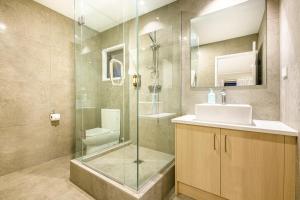 uma casa de banho com uma cabina de duche em vidro e um lavatório. em Takapuna International Motor Lodge em Auckland