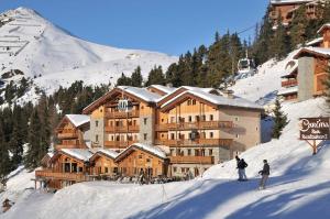 dos personas esquiando en la nieve frente a un lodge en Chalet Carte Blanche Juliette, en Belle Plagne