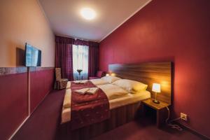 a bedroom with a large bed and a red wall at Hotel Czechia in Prague