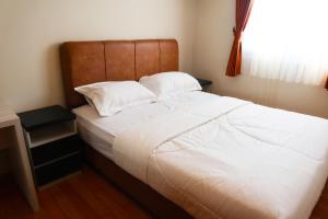 1 dormitorio con 1 cama grande con sábanas y almohadas blancas en MG Suites 1 Bedroom Apartment Sea View Semarang (KUMU SUITES) en Semarang