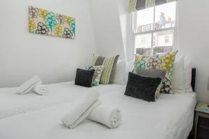 a room with two beds with pillows and a window at Marine Cottage - Parking - by Brighton Holiday Lets in Brighton & Hove