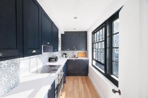 a kitchen with black cabinets and white counter tops at Worthing town house in Worthing