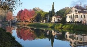 a river with houses and trees reflecting in the water at Hotel Villa Giulietta in Fiesso dʼArtico