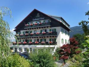 a large white building with flowers on the balcony at Seehotel Sissi in Zell am See