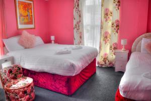 a bedroom with pink walls and a bed and a chair at Villa Rose in Great Yarmouth