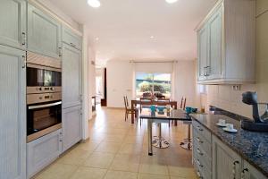 a kitchen with white cabinets and a dining room at Casa Tulipas in Loulé