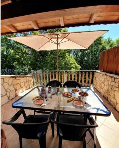 uma mesa com cadeiras e um guarda-sol num pátio em La casa di Olivia em Rocca di Cambio