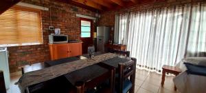 a kitchen with a table in a room with windows at Cozy Cottage +/- 500m from the beach in Cape Town