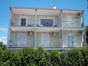 a tall white building with chairs on the balconies at Milos Apartments in Afitos