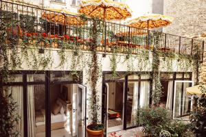 einen Balkon mit Pflanzen und Sonnenschirmen auf einem Gebäude in der Unterkunft Hôtel Monsieur Aristide in Paris