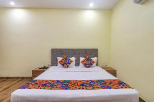 a bedroom with a large white bed with colorful pillows at FabExpress Le Gardenia in Patna