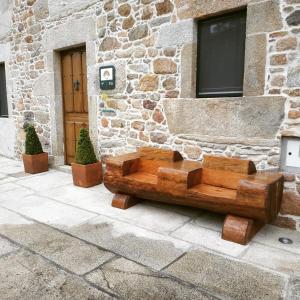 un banco de madera sentado frente a un edificio en Casa Rural Liñeiros, en Muxía