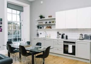 een witte keuken met een eettafel en stoelen bij ALTIDO Bold and Spacious 1bed home, near Haymarket train station in Edinburgh