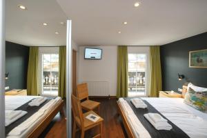 a bedroom with two beds and two windows at Seehotel Sissi in Zell am See