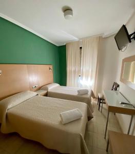 a hotel room with two beds and a television at Hotel Alamo in Alicante