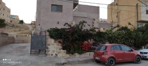 a small red car parked in front of a building at Nonna Aisha B&B in Wadi Musa