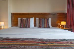 a large bed with two pillows and a wooden headboard at Antika Amman Hotel in Amman