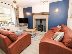 a living room with two leather couches and a fireplace at 1 Orchard View in Hathersage
