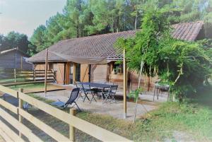 una casa con un tavolo e sedie di fronte di Les Gîtes du Grand Chêne a Saint-Paul-en-Born