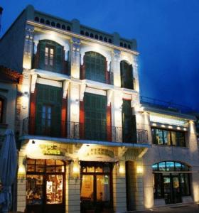 Un edificio iluminado con un balcón en la parte superior. en Astoria Hotel Traditional, en Komotiní