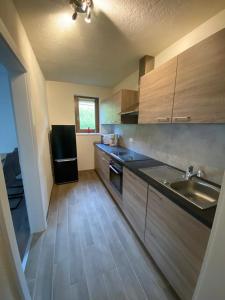 cocina con armarios de madera y nevera negra en Apartment GRANAT en Sankt Oswald