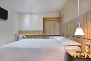 1 dormitorio con 1 cama blanca grande y TV en Presto Hotel, en Blumenau