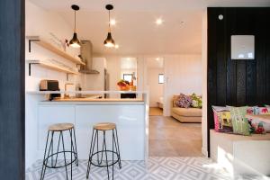 a kitchen and living room with a counter and stools at Beach and Vineyard Escape - Haumoana Beach Home in Haumoana