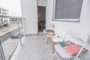 a balcony with chairs and a table and a window at Apartman Lena in Banja Koviljača