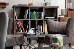 a bookcase with two chairs and a table in front of it at TRYP by Wyndham Köln City Centre in Cologne