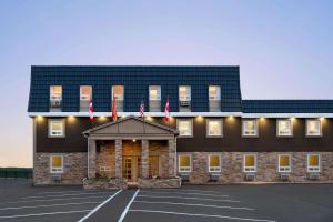 un grand bâtiment avec drapeaux dans un parking dans l'établissement Days Inn by Wyndham Fredericton, à Fredericton