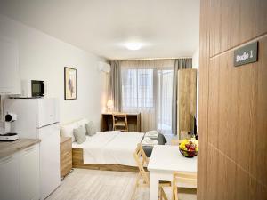 a hotel room with a bed and a table and a kitchen at Cozy Studio next to State Opera with Work Space in Stara Zagora