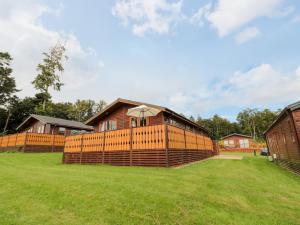 a wooden house with a fence in a field at Hillside View in Morpeth