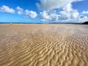 a beach with a person walking on the sand at Bungalow33 Benllech in Benllech