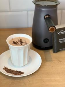 a cup of coffee on a plate next to a coffee maker at Bungalow33 Benllech in Benllech