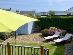 two chairs and a yellow umbrella next to a fence at Bungalow33 Benllech in Benllech