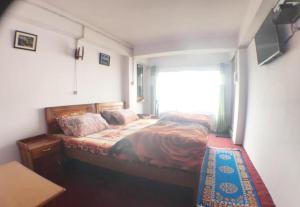 a small bedroom with a bed with a window at Khangsangma Guest House in Darjeeling