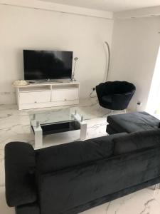 ein Wohnzimmer mit einem schwarzen Sofa und einem TV in der Unterkunft Luxusvilla Neubau 2 in Oberasbach