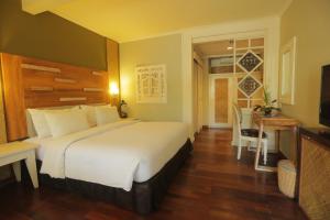 a hotel room with a large bed and a table at Peneeda View Beach Hotel in Sanur