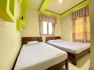 a bedroom with two beds and a window at Homestay Srikandi Syariah Dieng RedPartner in Diyeng