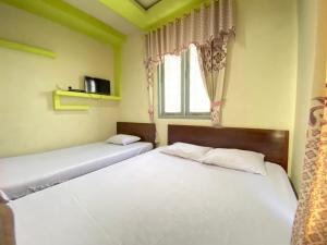 two beds in a room with a window at Homestay Srikandi Syariah Dieng RedPartner in Diyeng