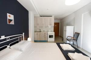 een slaapkamer met een wit bed en een keuken bij Aristotle's Studio in Kalamata