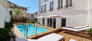 a swimming pool with two chairs and an umbrella on a deck at Casa BARR in Trafaria