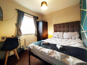 a bedroom with a bed and a desk and a window at Bankwell Guest House in Manchester