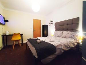 a bedroom with a large bed and a yellow chair at Bankwell Guest House in Manchester
