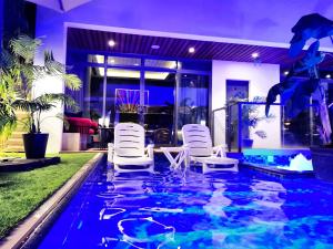 a swimming pool with white chairs in a house at G R A N D C H A L E T in Salalah