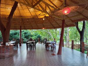 a restaurant with tables and chairs and a wooden ceiling at Nan De Panna Homestay in Nan